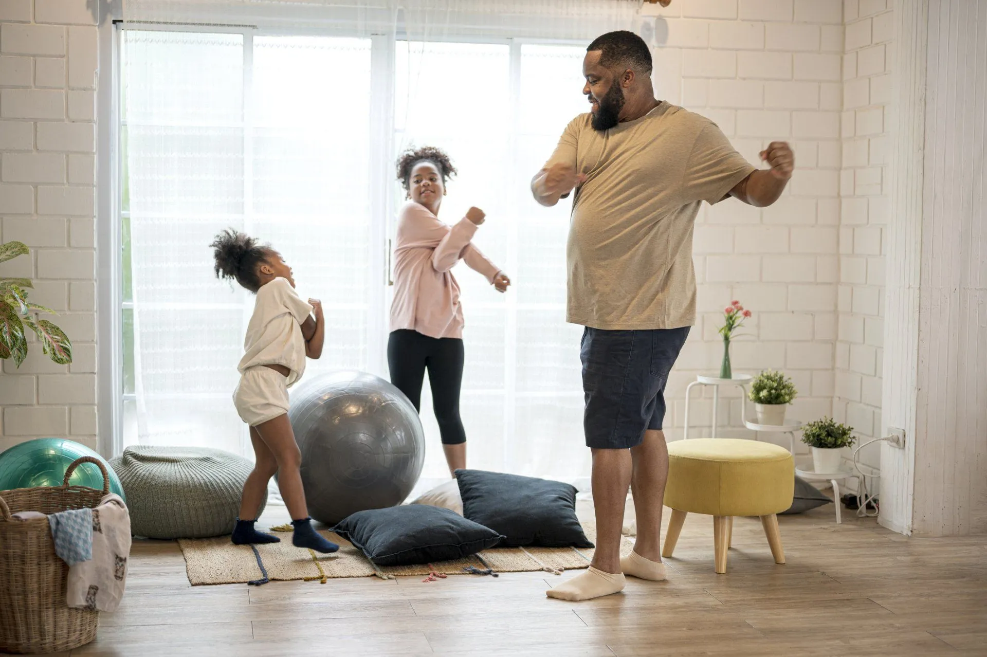 Father dancing with daughters in bright living room