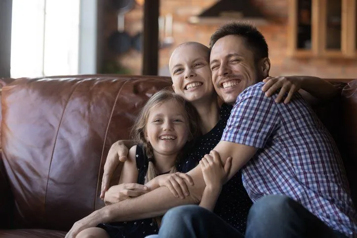 Smiling family hugging together on leather couch